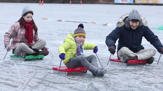 一家人乘坐雪橇滑过冰冻的水库/洪川，韩国视频素材