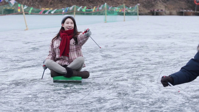 一对夫妇乘坐雪橇滑过冰冻的水库/洪川，韩国视频素材