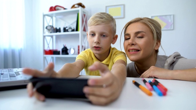 小男孩玩新手机游戏，妈妈给儿子提意见，消遣视频下载