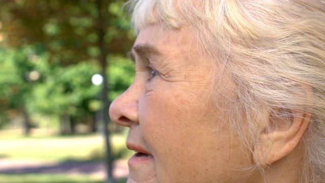 老年白种妇女等候休息公园，享受自然风光，宁静视频下载