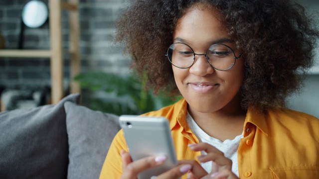 快乐的非裔美国少年在家里用智能手机笑视频素材