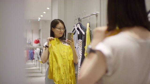中国女子在试衣间镜子前用智能手机自拍视频素材