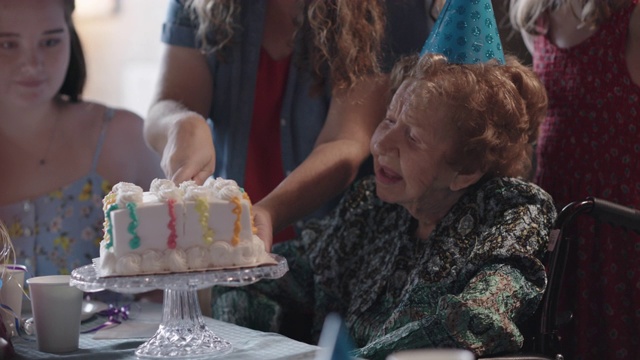 孙女在百岁生日派对上为祖母和曾孙们切蛋糕视频素材