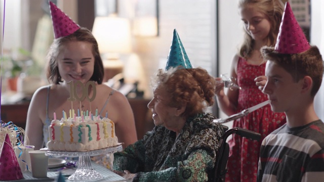 在太祖母百岁生日聚会上，吹灭了太祖母生日蛋糕上的蜡烛后，曾孙们一个个亲吻她视频素材