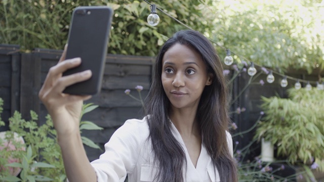 千禧女网红在花园里用智能手机自拍视频下载
