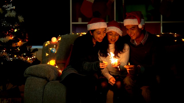 慢动作拍摄微笑的家庭玩圣诞烟花，而庆祝圣诞时间在一个客厅视频素材