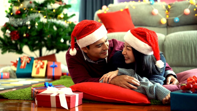 4K微笑情侣在有圣诞树背景的客厅庆祝圣诞时间视频素材