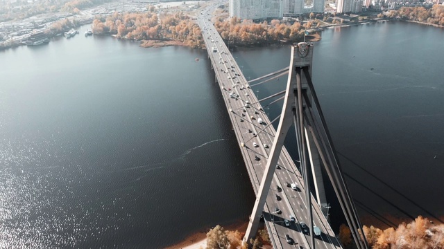 连接大都市两岸的大桥上飘扬着乌克兰国旗。无人机拍摄的混凝土桥与繁忙的汽车交通。无人机在美丽的城市景观和河流的桥梁上飞行。基辅,乌克兰视频素材