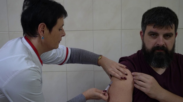 欧洲乌克兰基辅——2019年10月:接种疫苗预防病毒。护士给一个大胡子男子打针。视频素材