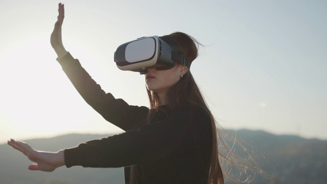 未来就是现在。虚拟现实的概念。女性戴着未来的VR盒头戴式耳机。女人在户外使用虚拟现实眼镜。女孩在vr头盔里玩冒险游戏，青春娱乐，休闲活动视频素材