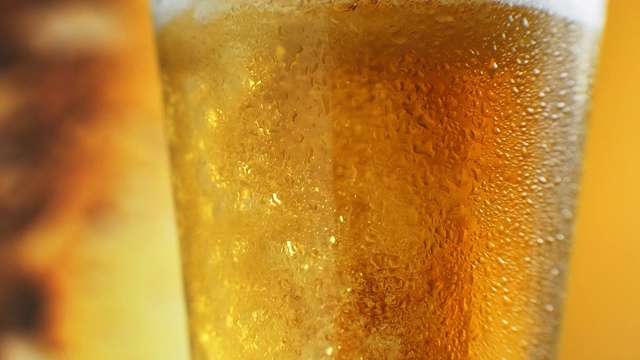啤酒倒进有角的玻璃杯里。异丙醇在水龙头。冰镇淡啤酒在玻璃杯中与水滴。精酿啤酒形成波浪接近。新鲜和泡沫。酒吧的背景。酿酒厂精酿啤酒视频素材