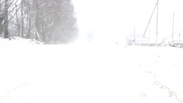 他的车沿着多雪的道路行驶，冬天里有一场强烈的暴风雪视频素材