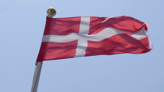 一个温暖、美丽、明亮的夏日，丹麦国旗骄傲地在风中飘扬的慢镜头。视频素材