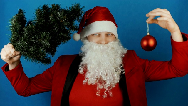 2019年新年，男人像圣诞老人一样带着圣诞树和红球玩具，在蓝色的背景上视频下载