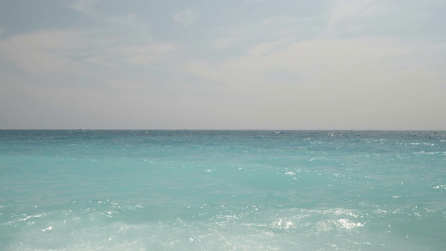 4k慢镜头碧绿的地中海海水拍打着法国尼斯的卵石海滩。在一个明媚温暖的夏日，展现了清澈美丽的湖水。视频素材