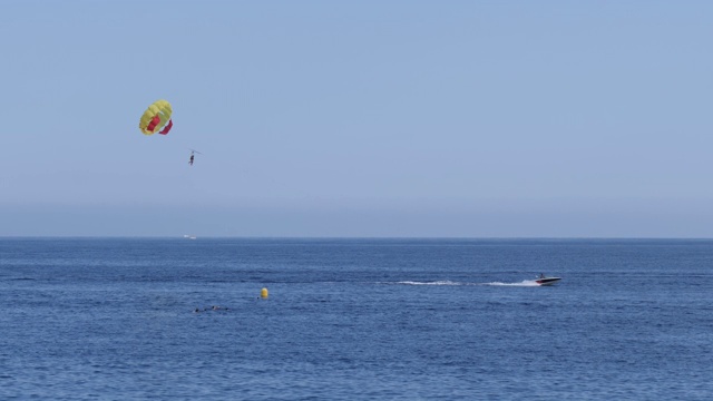 4k慢镜头显示法国尼斯海滩附近的快艇和滑翔伞水上运动。展示了度假者在一个明媚温暖的夏日享受寻求刺激的活动。视频素材