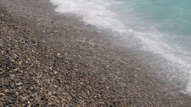美丽的地中海热带水域冲击着法国尼斯的卵石海滩。在一个明媚温暖的夏日，展现了清澈美丽的湖水。视频素材