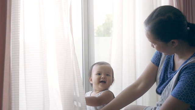 亚洲女婴与她的母亲玩窗帘捉迷藏视频素材
