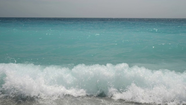 4k慢动作水晶彩色的地中海海水撞击了法国尼斯的卵石海滩。在一个明媚温暖的夏日，展现了清澈美丽的湖水。视频素材