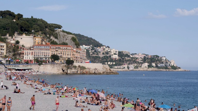 家人、朋友和度假者在法国尼斯的海滩享受阳光和游泳。在一个明媚温暖的夏日，展现了清澈美丽的湖水。视频素材
