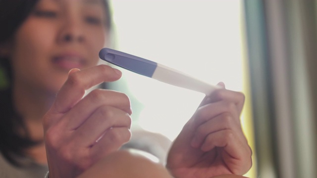 怀孕测试在微笑女性的手视频素材