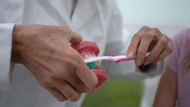 女牙医的近距离展示年轻女孩如何刷牙正确刷牙的牙齿盒视频下载