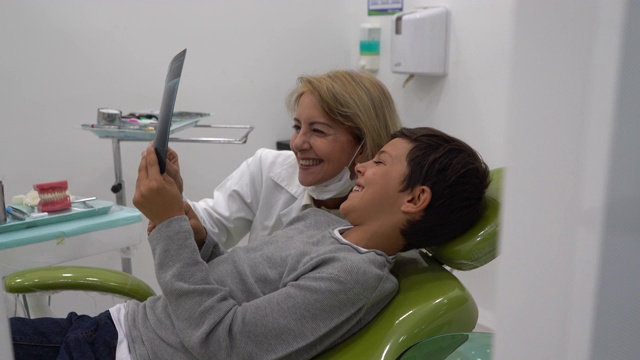 一名小男孩和一名女牙医在会诊期间一边看牙齿x光，一边愉快地交谈视频素材