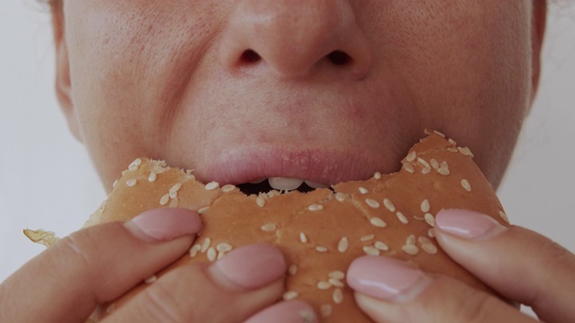 吃汉堡的女人，不健康的饮食，闭上嘴唇视频素材