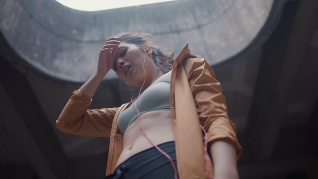 日本女子在运动服装与耳机捕捉呼吸在东京，日本。视频素材