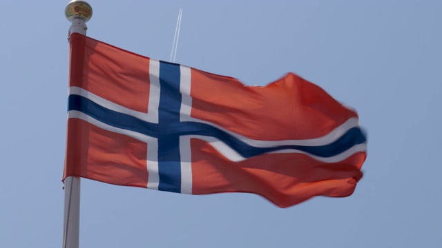 挪威国旗在一个温暖、美丽、明亮的夏日骄傲地在风中飘扬的慢镜头。视频素材