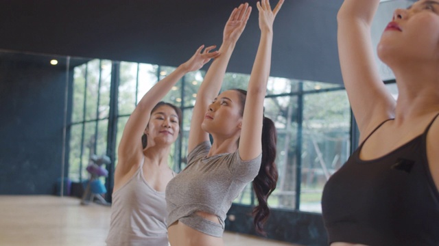 年轻的亚洲运动员与教练练习瑜伽课。亚洲女性群体在健身室锻炼健康的生活方式。体育活动，体操或芭蕾课。缓慢的运动。视频下载