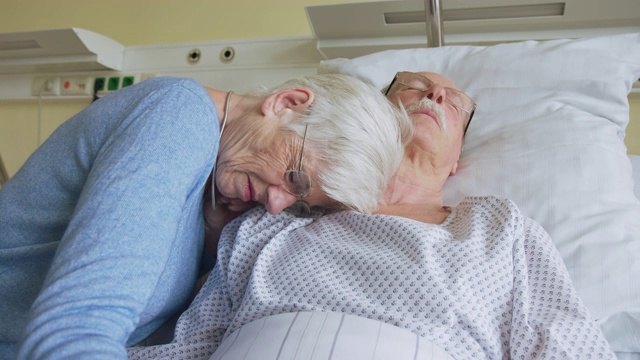 在医院病床上，一位老妇人在她生病的丈夫旁边哭泣视频素材