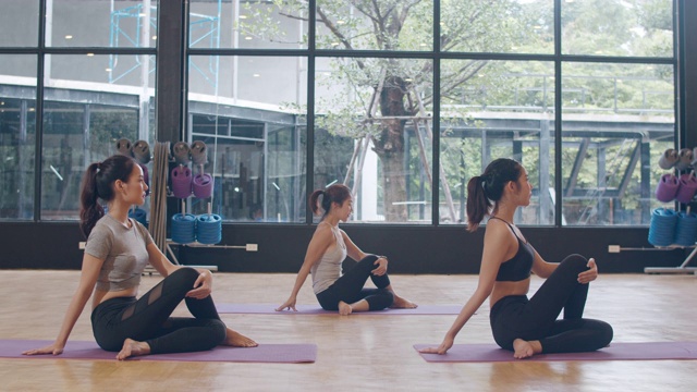 年轻的亚洲体育有吸引力的人练习瑜伽课与教练。亚洲女性群体在健身室锻炼健康的生活方式。体育活动，体操或芭蕾课。视频下载