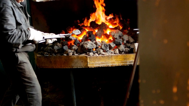 铁匠将红热的金属件在炉内翻转，对金属进行热处理、硬化和加热、锻造、慢动作视频素材