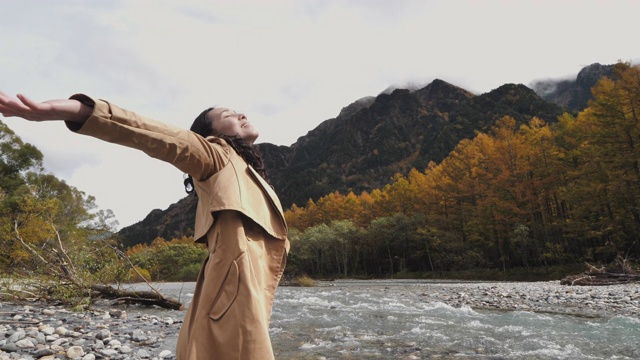 年轻的亚洲女子站在秋叶色的自然双臂伸展自由和积极的情绪视频素材