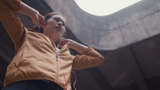 日本女子在运动服装与耳机捕捉呼吸在东京，日本。视频下载