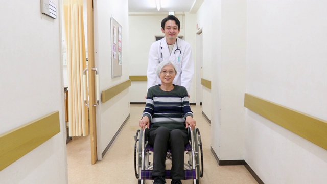 医生用轮椅推着一位老年病人穿过医院视频素材