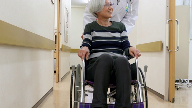 医生用轮椅推着一位老年病人穿过医院视频素材