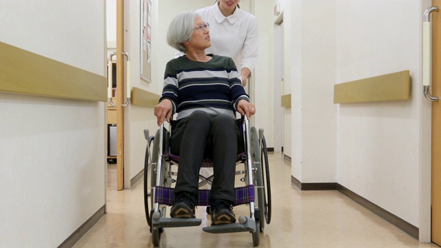 护士推着一位坐轮椅的老年病人穿过医院视频素材
