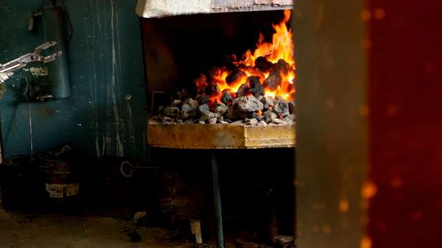 铁匠将红热的金属件在炉内翻转，对金属进行热处理、硬化和加热、锻造、慢动作视频素材