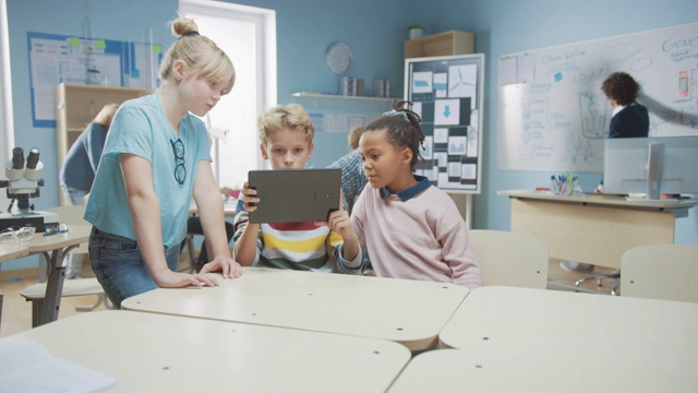 小学计算机科学课:两个女孩和男孩使用数字平板电脑与增强现实软件，他们兴奋，充满好奇。在STEM，玩耍，学习的孩子们视频素材