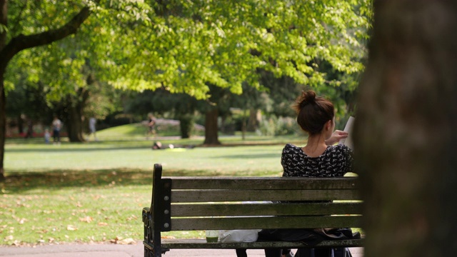 女人在公园的长椅上看书视频素材