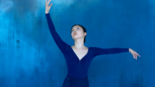 专业芭蕾舞演员的舞蹈感官，使平滑的运动与她的手在一个蓝色的背景视频下载