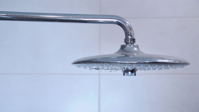 水从淋浴喷头和水龙头在现代浴室。雨淋转过来，天花板喷头特写在淋浴间。视频素材
