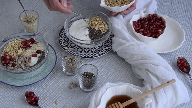 个人观点，妇女的手准备健康的早餐，什锦麦片与生石榴，向日葵，芝麻和奇亚籽。视频素材
