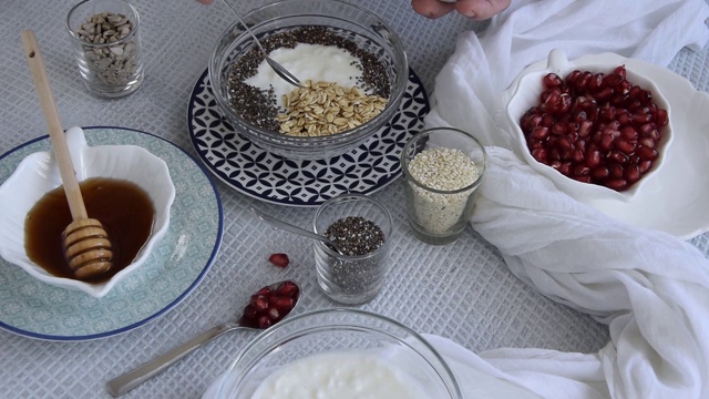 个人观点，妇女的手准备健康的早餐，什锦麦片与生石榴，向日葵，芝麻和奇亚籽。视频素材