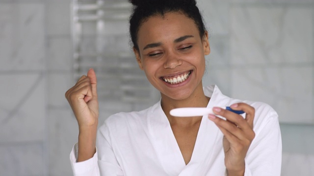快乐的非洲妇女抱阳性测试庆祝怀孕在浴室视频素材
