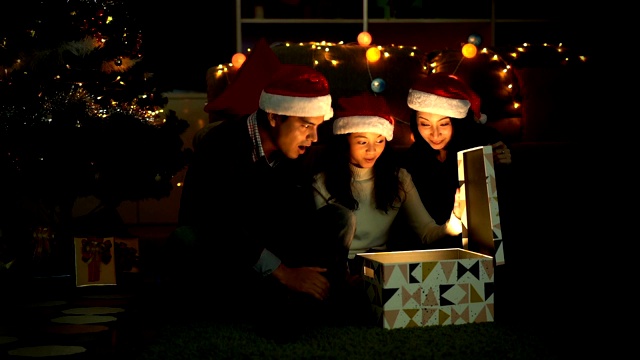 慢动作拍摄的欢乐的家庭打开惊喜的礼盒与一个闪亮的爆炸光线视频素材