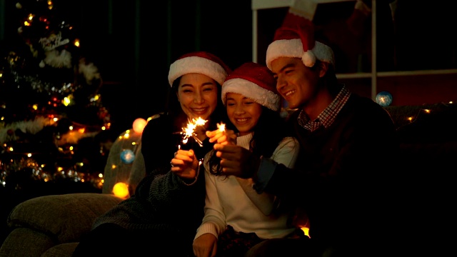微笑的女儿与她的父母在圣诞节庆祝时间玩圣诞烟花视频素材