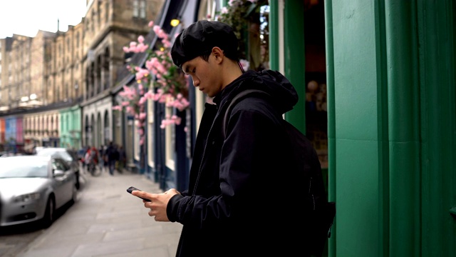 在欧洲，一名年轻的亚洲男子用手机随意地发短信视频素材